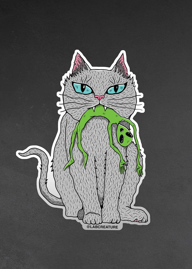 Photo of a vinyl sticker featuring a grey cat holding a green alien in their mouth